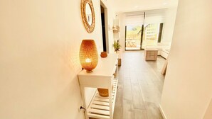 A hallway with a white bench, a wall-mounted mirror, and a floor lamp.