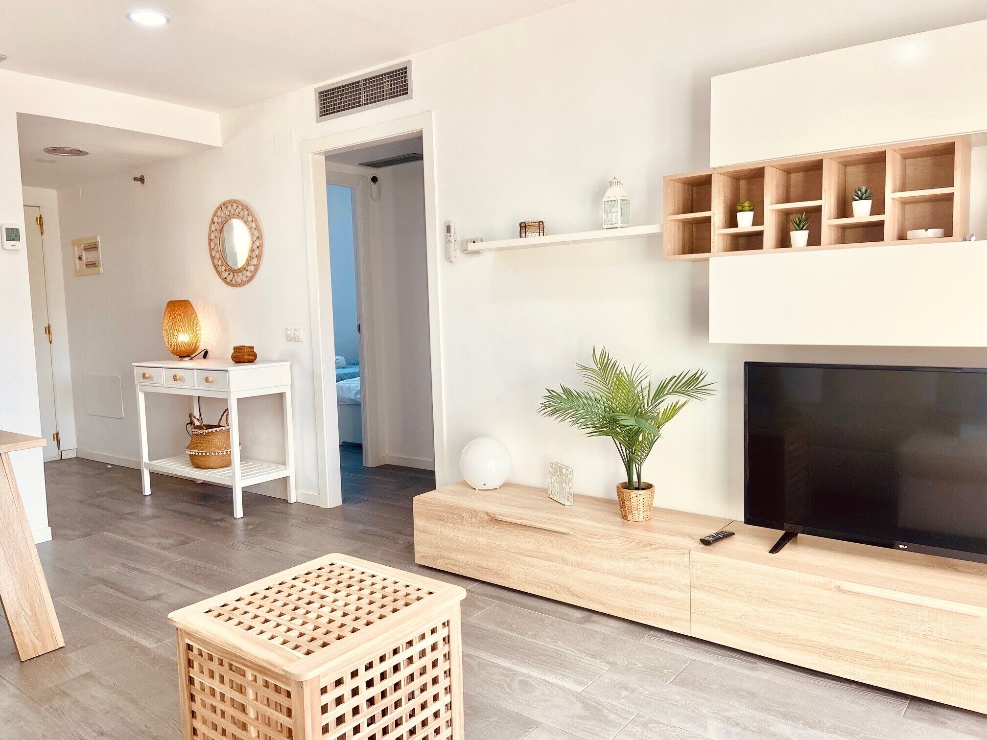 Uma sala de estar moderna com televisão, um console de madeira e um vaso de planta.