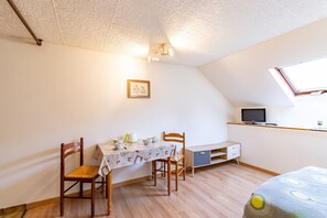 A room with a dining table, chairs, a television, and a window. - Studio La Résidence du Vieux Four with Shared Pool Near Sarlat (Saint Geniés)
