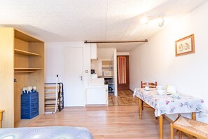 A room with a dining table, chairs, a kitchen area, and a wardrobe. - Studio La Résidence du Vieux Four with Shared Pool Near Sarlat (Saint Geniés)