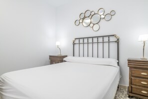 A neatly made bed with a headboard, two bedside tables with lamps, and a wall-mounted mirror.