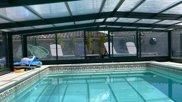A swimming pool with a glass ceiling, surrounded by a decorative border.