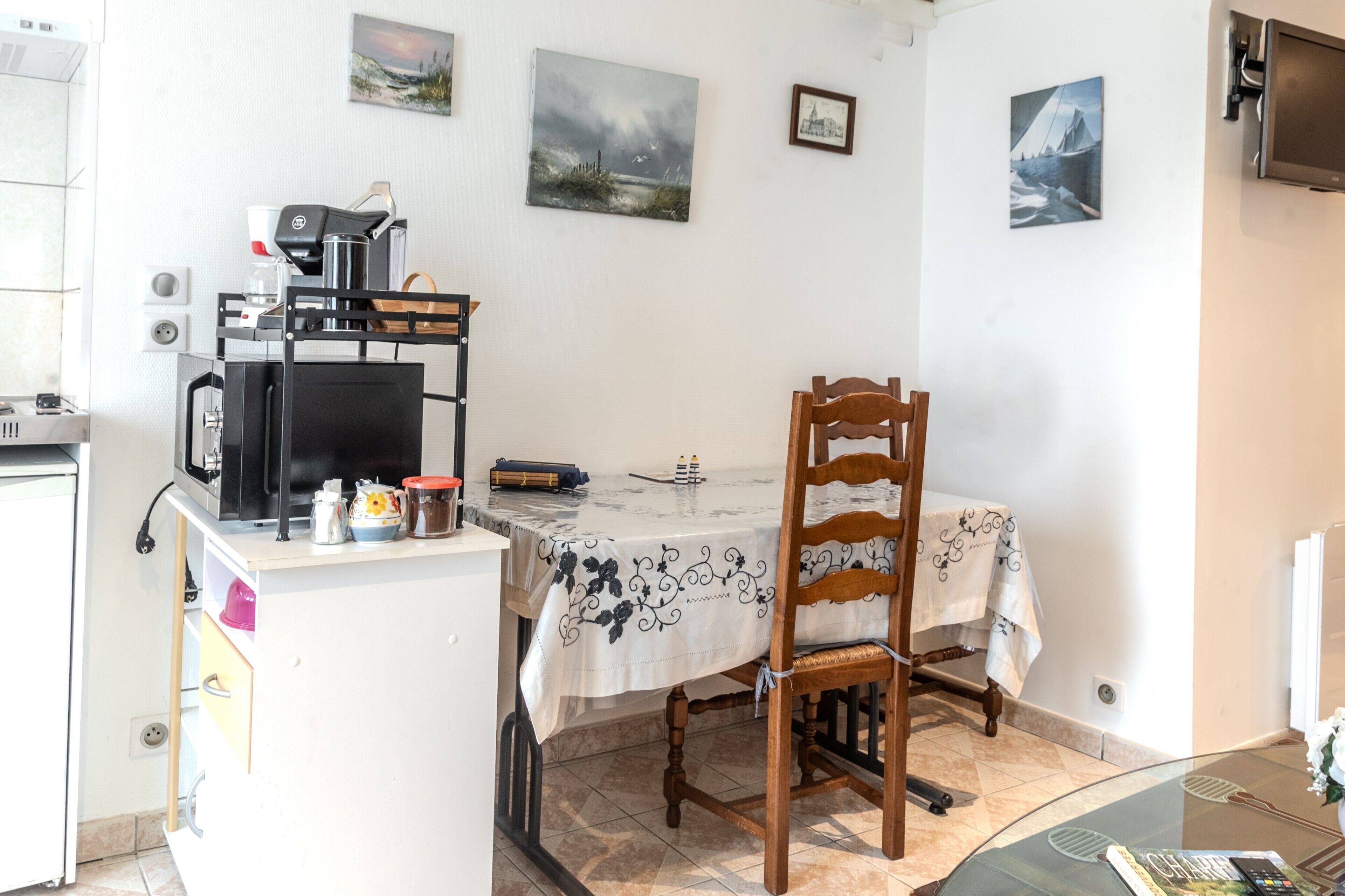 A dining area with a table, chairs, a coffee machine, and artwork on the walls.