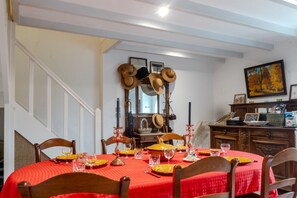 Uma sala de jantar com toalha vermelha, cadeiras de madeira e uma escada.