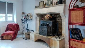A room with a fireplace, a red armchair, a bookshelf, and a window.