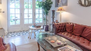 A living room with a glass coffee table, leather sofa, and a door leading to a garden.