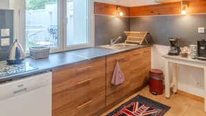 A modern kitchen with wooden cabinets, a built-in sink, and a coffee machine. - Holiday Home 'La Maison D'Éloi' with Shared Pool, Private Terrace & Wi-Fi (Montignac-Charente)