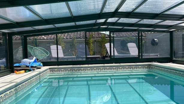 A swimming pool with a glass ceiling, surrounded by a decorative tiled border. - Holiday Home 'La Maison D'Éloi' with Shared Pool, Private Terrace & Wi-Fi (Montignac-Charente)