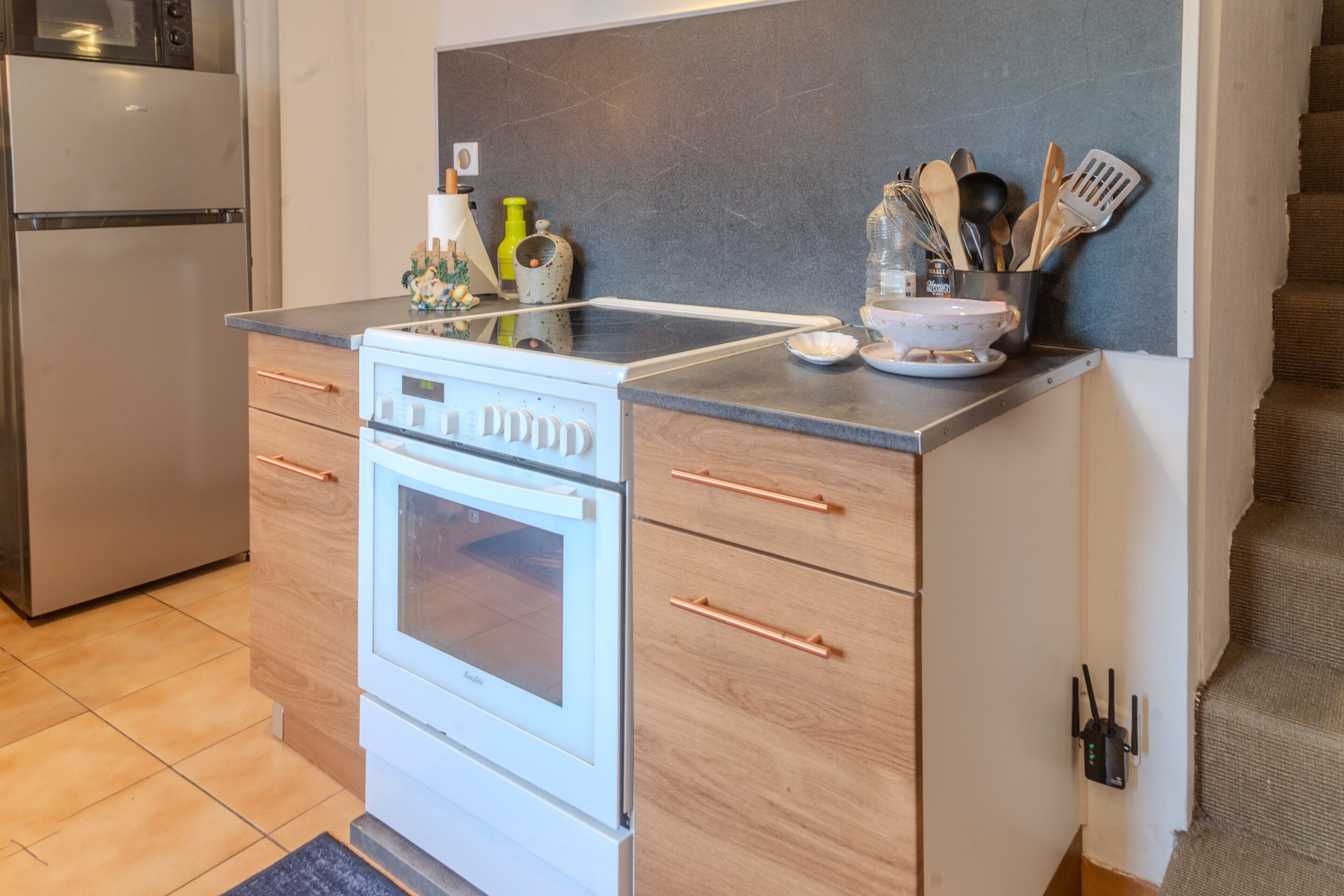 A compact kitchen with a built-in oven, a microwave, and a stainless steel refrigerator.