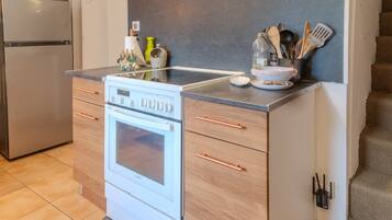 A compact kitchen with a built-in oven, a microwave, and a stainless steel refrigerator.
