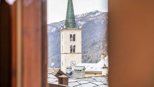 En kirke med et tårn, omgivet af bygninger og bjerge.
