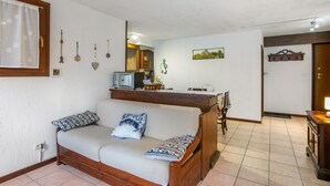 En stue med sofa, fjernsyn, et træskab og et vægmonteret ur.
