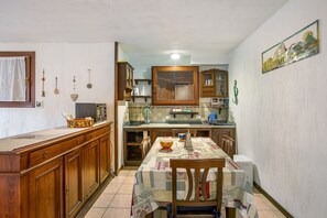 Une cuisine avec des meubles de rangement en bois, une table à manger avec des chaises et un mur recouvert de carreaux.