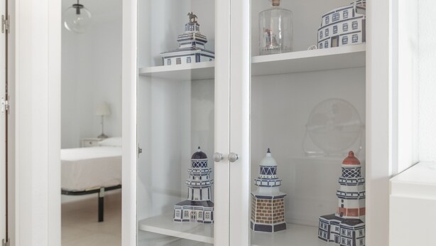 A room with a bed, a nightstand, and a cabinet with decorative items. - Casa Ricardo - Vacation Home Near the Beach in Barbate (Barbate)