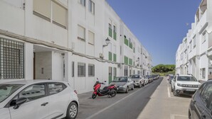 A street with parked cars and a row of white buildings with green shutters. - Casa Ricardo - Vacation Home Near the Beach in Barbate (Barbate)