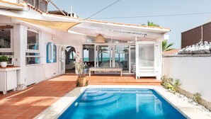 Une piscine dotée d’un parasol, d’un espace salon couvert et offrant une vue sur la mer.