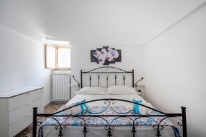 A bedroom with a bed, a radiator, a window, and a wall-mounted picture.