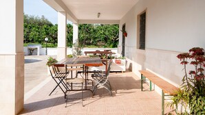 An outdoor patio with a table and chairs, a bench, and potted plants.