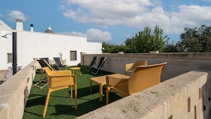 Una terrazza sul tetto con posti a sedere all'aperto e vista su un edificio bianco.