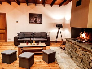 Un salon chaleureux avec une cheminée, un canapé, une table basse et deux poufs.