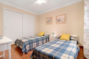 A bedroom with two beds, a nightstand, a lamp, and a wardrobe.
