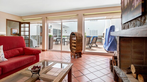 Un salon avec un canapé rouge, une table basse en verre, un tonneau en bois et une cheminée.