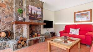 Un salon avec une cheminée en pierre, un canapé rouge et une table basse en bois.