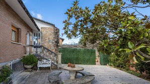 A courtyard with a stone table, a white bench, a staircase, and a green hedge.
