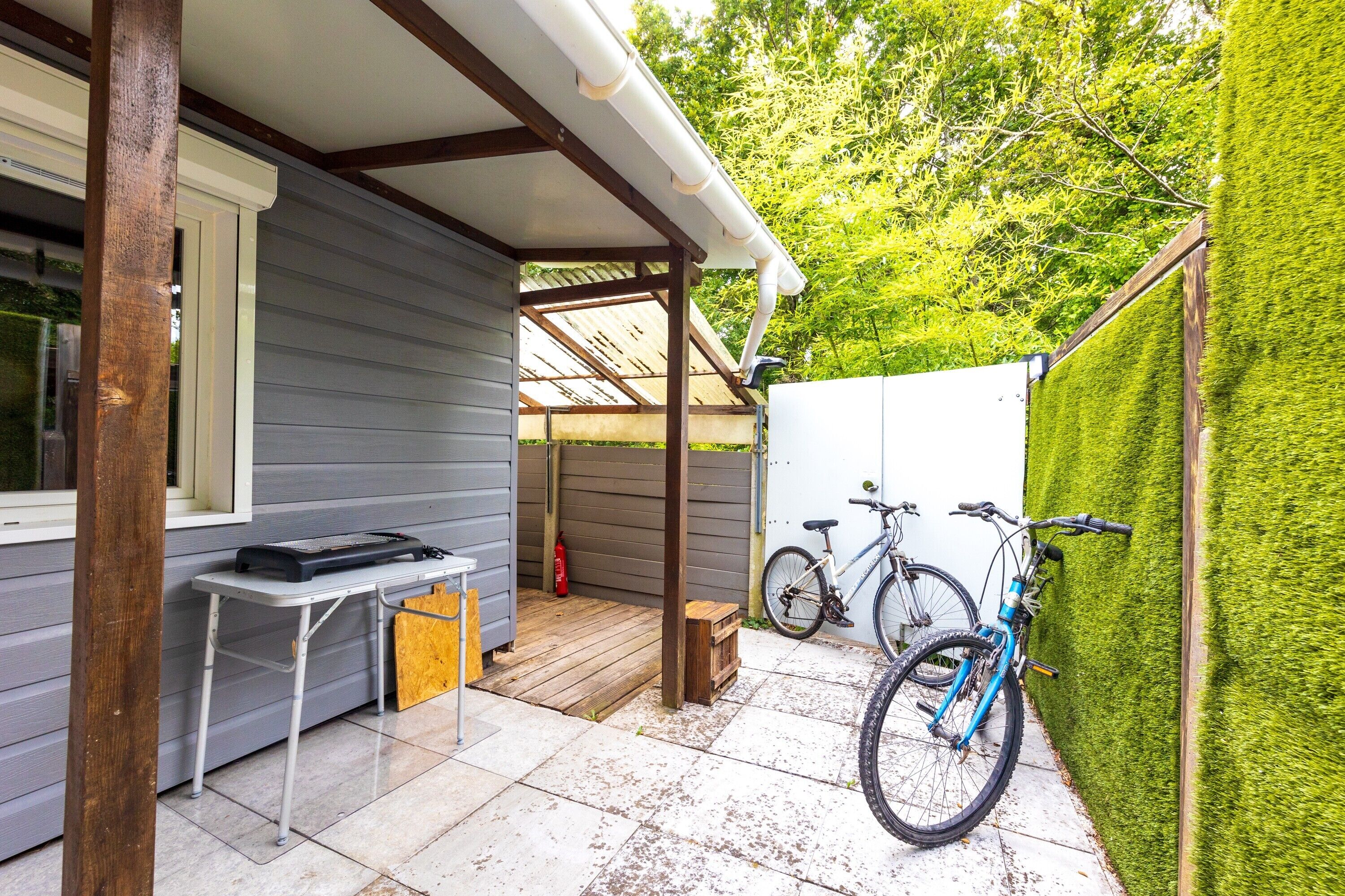Un portico coperto con tavolo e sedie, una bicicletta e un estintore.