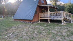 Eine Holzhütte mit geneigtem Metalldach, einer Holzterrasse und einer kleinen Veranda.