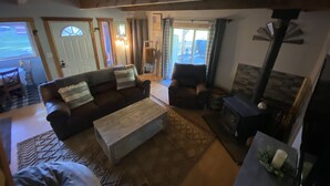 Ein gemütliches Wohnzimmer mit Kamin, einer Couch und einem Couchtisch. Eine Tür führt auf einen Balkon.