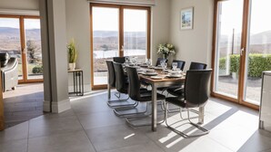 A dining area with a table set for six, large windows with a view, and a modern interior design.