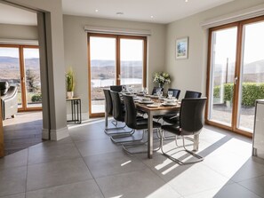 Ein Essbereich mit einem für sechs Personen gedeckten Tisch, großen Fenstern mit Aussicht und einem modernen Interieur.