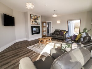 A modern living room with a flat-screen TV, a fireplace, a sofa, and a coffee table.