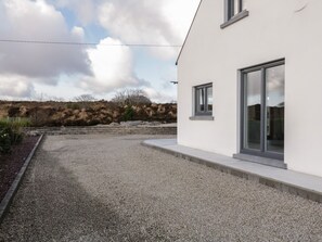 A modern building with a gravel driveway and a landscaped area with shrubs.