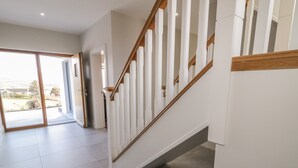 A modern interior with a staircase, a glass door leading outside, and a tiled floor.