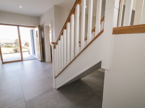 Ein modernes Interieur mit einer Treppe, einer Glastür, die nach draußen führt, und einem gefliesten Boden.
