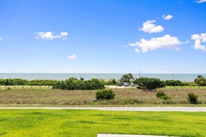 Une vue sur la côte, avec une zone herbeuse, un chemin pavé et quelques voitures garées.