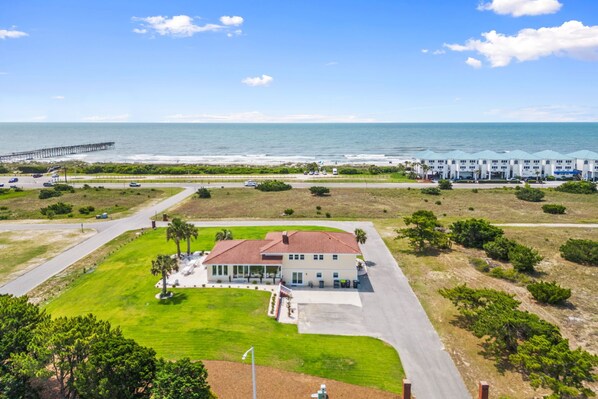 Un hôtel situé sur la côte, avec un grand bâtiment, une jetée et une plage en arrière-plan.