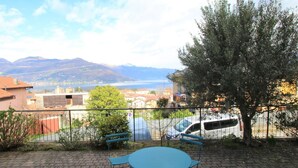 Un patio con un tavolo rotondo e quattro sedie, con vista su una città e montagne, con un lago o mare in lontananza.