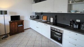 Una cucina moderna con mobili bianchi, un piano di lavoro nero e un forno integrato.