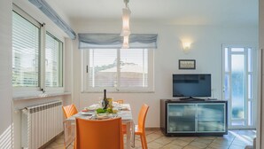 A dining area with a table set for two, a television, and a cabinet. - Nice apartment for 4 people with WIFI, A/C, TV and patio (Capanne-prato-cinquale)