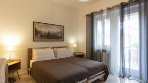 Une chambre à coucher avec un lit, des lampes de chevet, un tableau au mur et une fenêtre avec des rideaux.