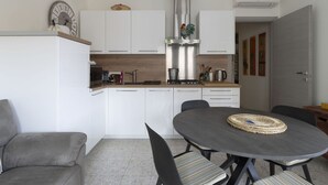 Une cuisine moderne avec des meubles blancs, un plan de travail en bois et un coin repas comprenant une table ronde et des chaises.