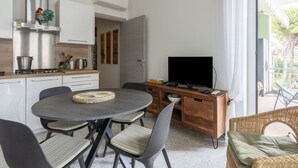 Une cuisine moderne avec un coin repas, un téléviseur à écran plat et un canapé en osier.