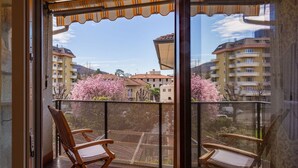 A balcony with two wooden chairs and a yellow awning.