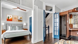 A bedroom with a bed, a ceiling fan, and a staircase leading to an upper level. - Historic Shaw Home • Sleeps 14 • Near Zoo & Arch (St. Louis)