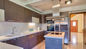 Una cocina moderna con armarios de madera oscura, electrodomésticos de acero inoxidable y una isla central.