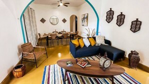 A living room with a sofa, armchairs, a coffee table, and a dining area with chairs and a table.