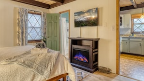 Een gezellige kamer met een bed, een open haard, een eethoek en een keuken.